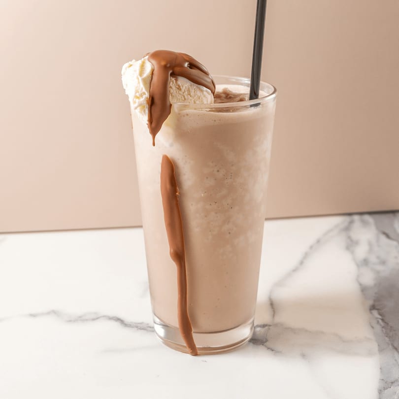 Chocolate milkshake with a scoop of vanilla ice cream and chocolate syrup drizzle.